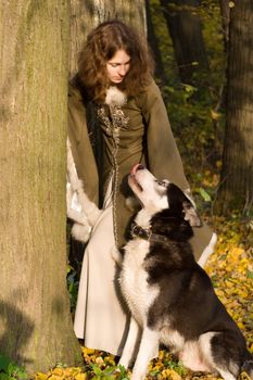 Lady in medieval dress and dog in the forest
