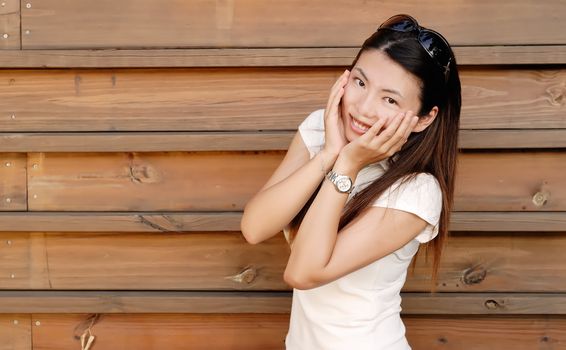 There is a smiling Asian modern lady in wooden background.