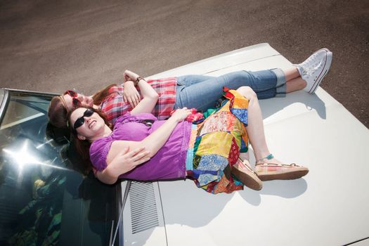 Women resting on the hood of an old car