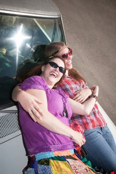 Women resting on the hood of an old car