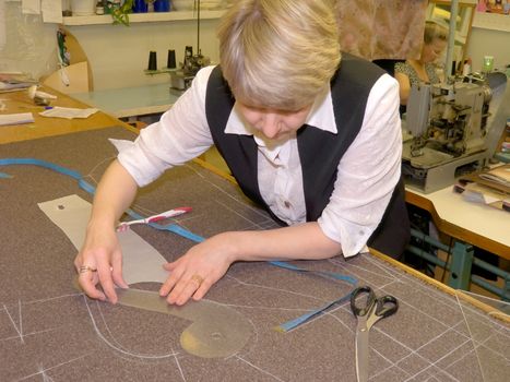 The woman, the fashion designer carries out the drawing of a pattern on a fabric.