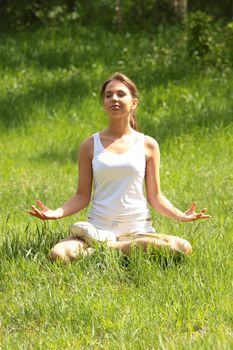 Beautiful young woman meditating outdoors