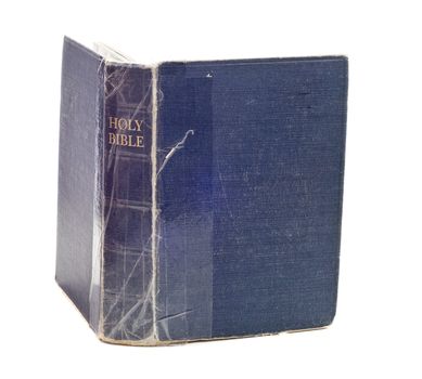 An old blue bible is being held together with tape and isolated against a white background