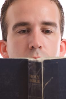 Closeup view of a young man reading an old bible, isolated against a white background
