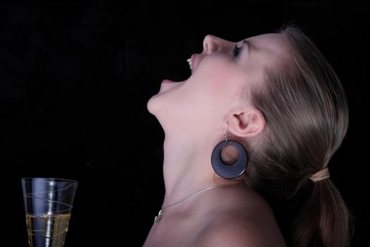 Beautiful blonde with a champagne glass screaming - on black background.