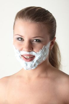 Happy pretty young woman with white beard made of shaving foam over white background
