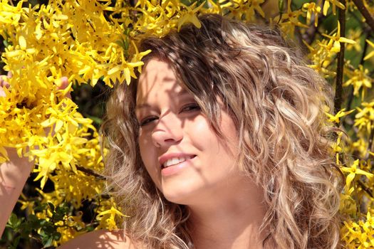 Blond young woman in yellow forsythia flowers - portrait