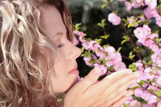 Beautiful blond woman between tree with pink flowers - portrait
