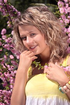 Beautiful blond woman between tree with pink flowers - portrait