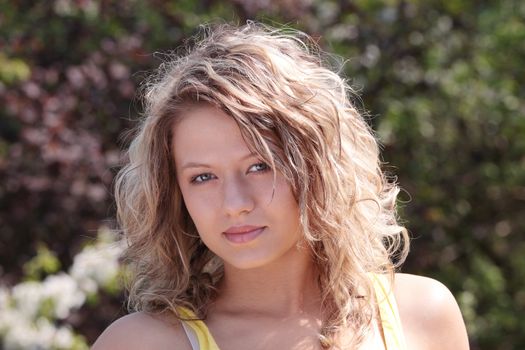 Beautiful blond woman against tree with flowers - portrait