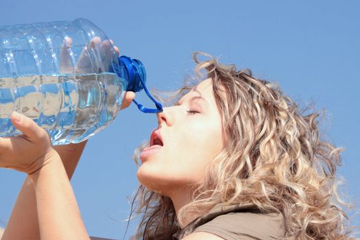 Thirsty blond woman on desert drink from big bottle of water.