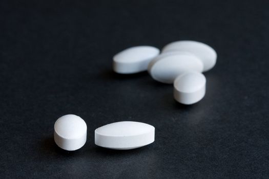 White medicine pills isolated on black background