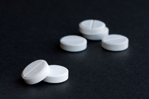 White medicine pills isolated on black background