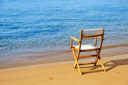 An empty chair on a golden sandy beach near the water