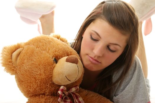 Beautiful teenager holding a teddy bear - isolated on white background