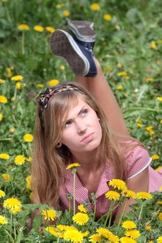 Beautiful young, blond woman relaxing in the grass and flowers