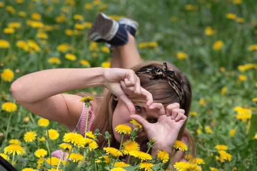 Beautiful young, blond woman relaxing in the grass and flowers