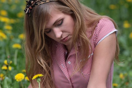 Beautiful young, blond woman relaxing in the grass and flowers