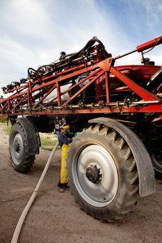 Filling chemical in a high clearance sprayer with proper safety equipment.