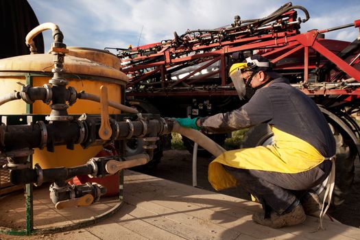 A farmer filling up a spraying practicing good chemical safety