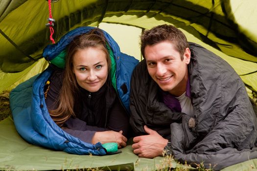A happy couple in a tent looking at the camera