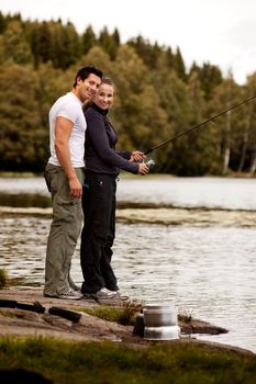 A man and woman fishing on a forest lake