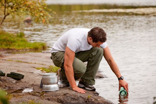 A young male adult fetching fresh water from a forest lake