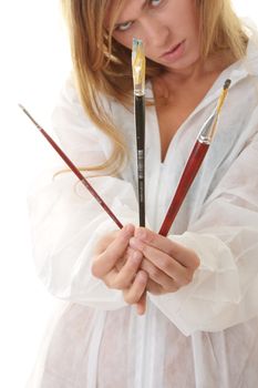 A female blond artist in white uniform with brushes - painting