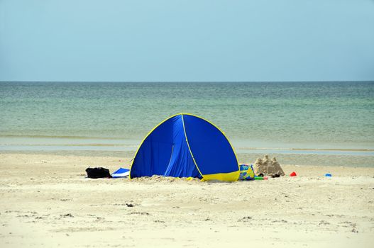 A blue beach tent with the ocean in front