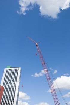 A Red Tower Crane Jib and a White Apartment Block under a blue sky