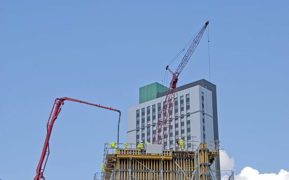 Red Tower Crane and Concrete Pump on a costruction Site with an Apartment Block in Background