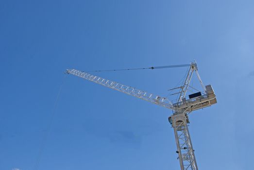 A White Tower Crane of a city construction site against a blue sky