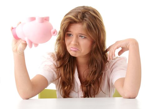 Young beautiful woman siting at the desk with piggy bank (money box), isolated on white background