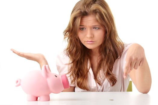 Young beautiful woman siting at the desk with piggy bank (money box), isolated on white background