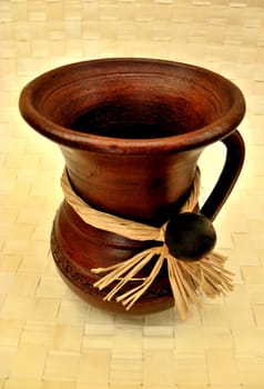 Jug from wood on the gird and cream-coloured background. 