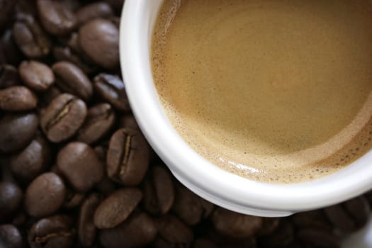 close-up of espresso cup with coffee beans around