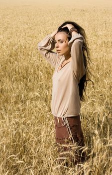 Attractive girl standing in wheat field and hold her head