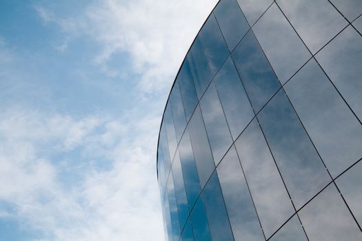 Modern round building reflecting the sky and clouds.