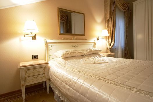 Wide bed and mirror in modern hotel