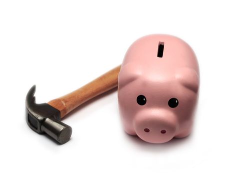 A cute piggy bank isolated on a white background, next to a hammer.
