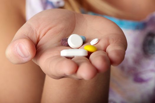 Young woman holding lot of pills isolated on black background