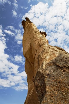 extreme close up and unusual angle of foot to top of fairy chimney into the clouds of Cappadocia, Turkey, portrait, crop space, copy space with blue cloudy sky