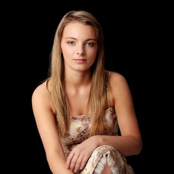Young beautiful woman in gold dress portrait isolated on black background