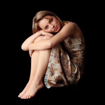 Young beautiful woman in gold dress portrait isolated on black background
