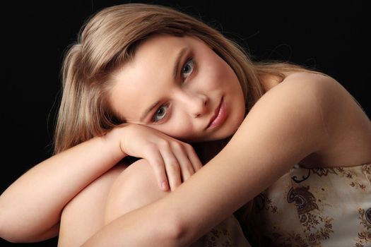 Young beautiful woman in gold dress portrait isolated on black background