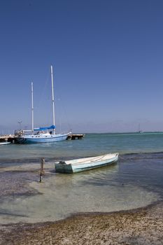 A small wooden rowboat is tied in the shallows close to a beautiful beach in the Gulf of Mexico.