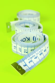A measuring tape isolated agaist a lime green background