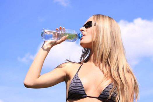 Girl drinking water against blue sky in sunny day