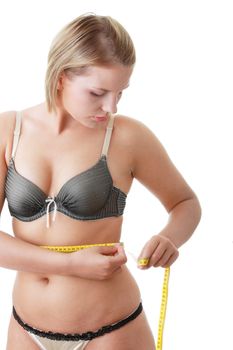 A little bit fat young woman mesuring her body isolated on white background