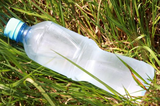 Cold water bottle lays among a grass (natural)